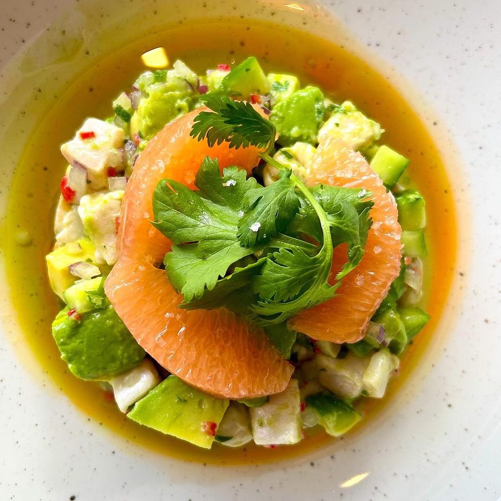 Overhead of ornate seafood dish, garnished with cilantro and brown broth