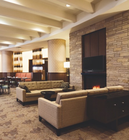 Lobby featuring warm tones and a large fireplace with a cozy sitting area inside of the Hilton Garden Inn in Harbor East
