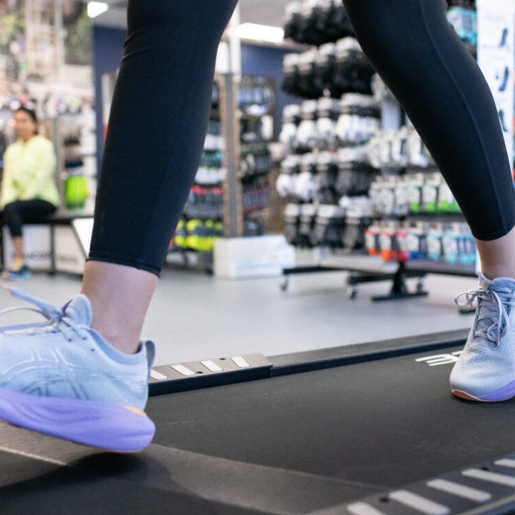 Closeup of women in running shoes walking swiftly on treadmill inside Charm City Running shoe store
