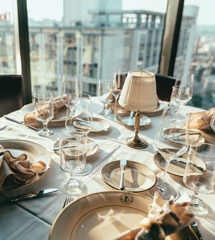 Fine dining table setting on white tablecloth at The Bygone overlooking high-rise window view of Baltimore City