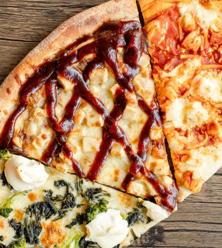 Closeup of three different pizza slices joint next to each other with various sauces and toppings