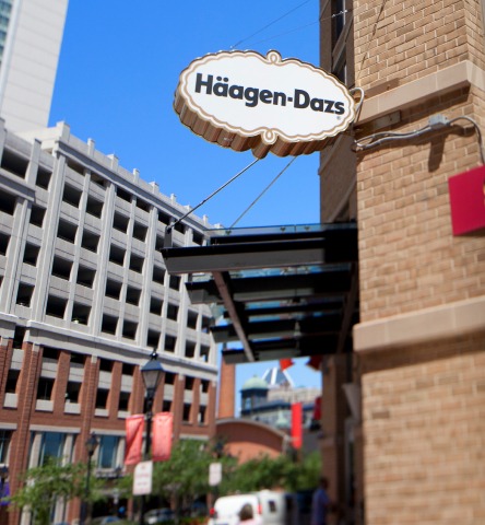 Haagen Daaz brick storefront with store sign hanging over black awning in city