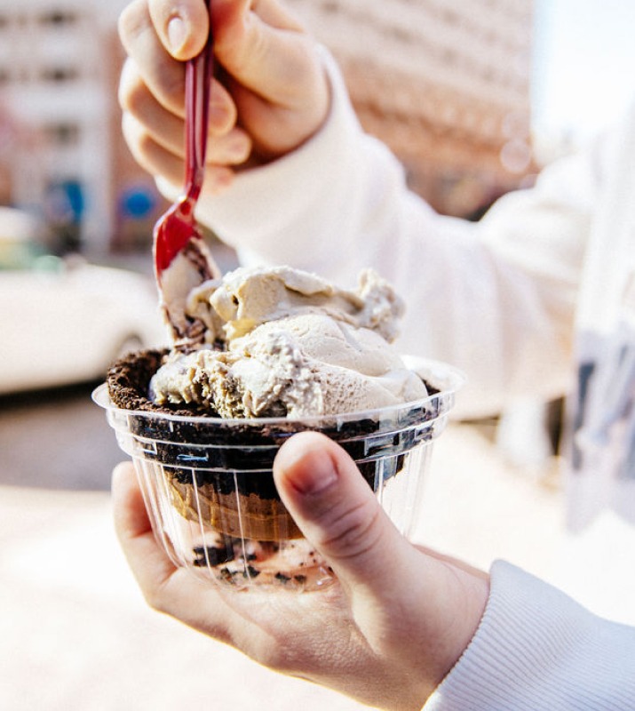 Closeup of hands spooning into a waffle cone ice cream bowl