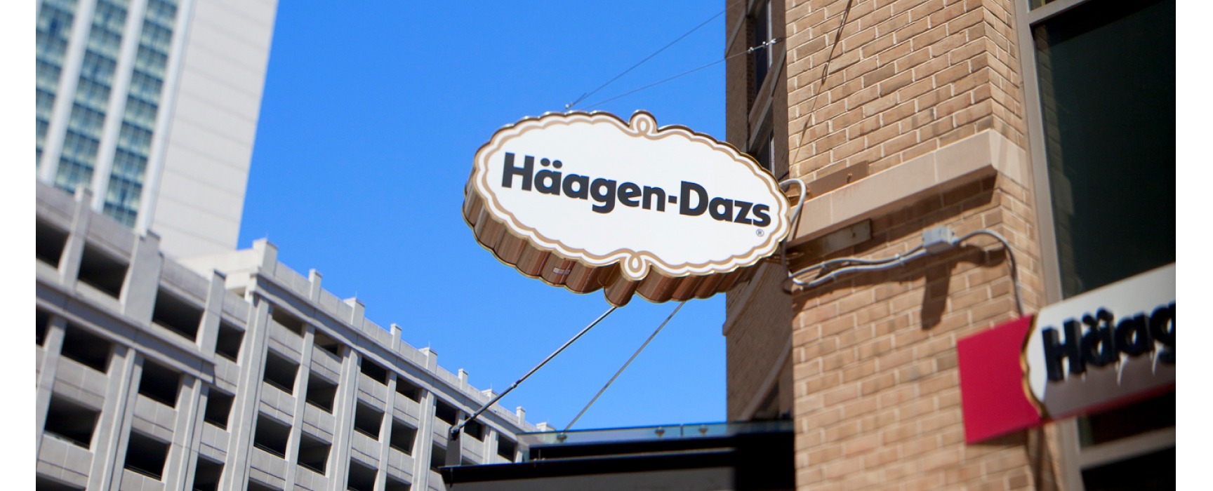 Haagen Daaz brick storefront with store sign hanging over black awning in city