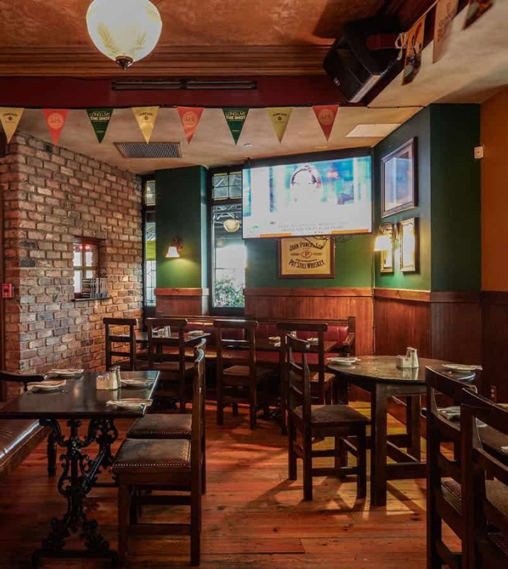 Cozy low-lighting interior of James Joyce Pub dining area featuring green, wood, and brick walls