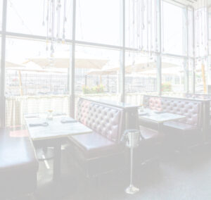 Interior of leather booth dining area at Loch Bar surrounded by ornate light fixtures and ceiling to floor windows with white graphic overlay