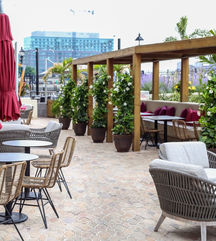 Stone patio outdoor dining at Maximon restaurant, featuring swanky booths, modern furniture and greenery