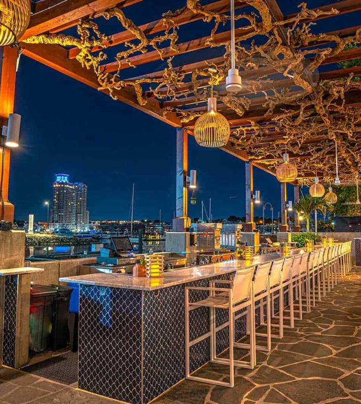Night view of Ouzo Beach outdoor bar with modern ornate decor overlooking the harbor and skyline