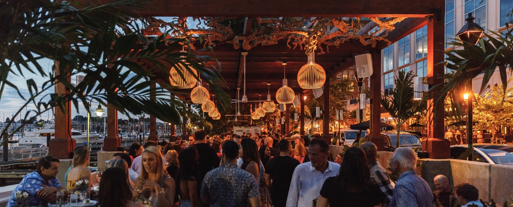 Dimly lit outdoor chic bar packed with people and surrounded by tropical greenery