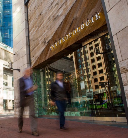 Two men whiz by the Anthropologie storefront in the center of Harbor East
