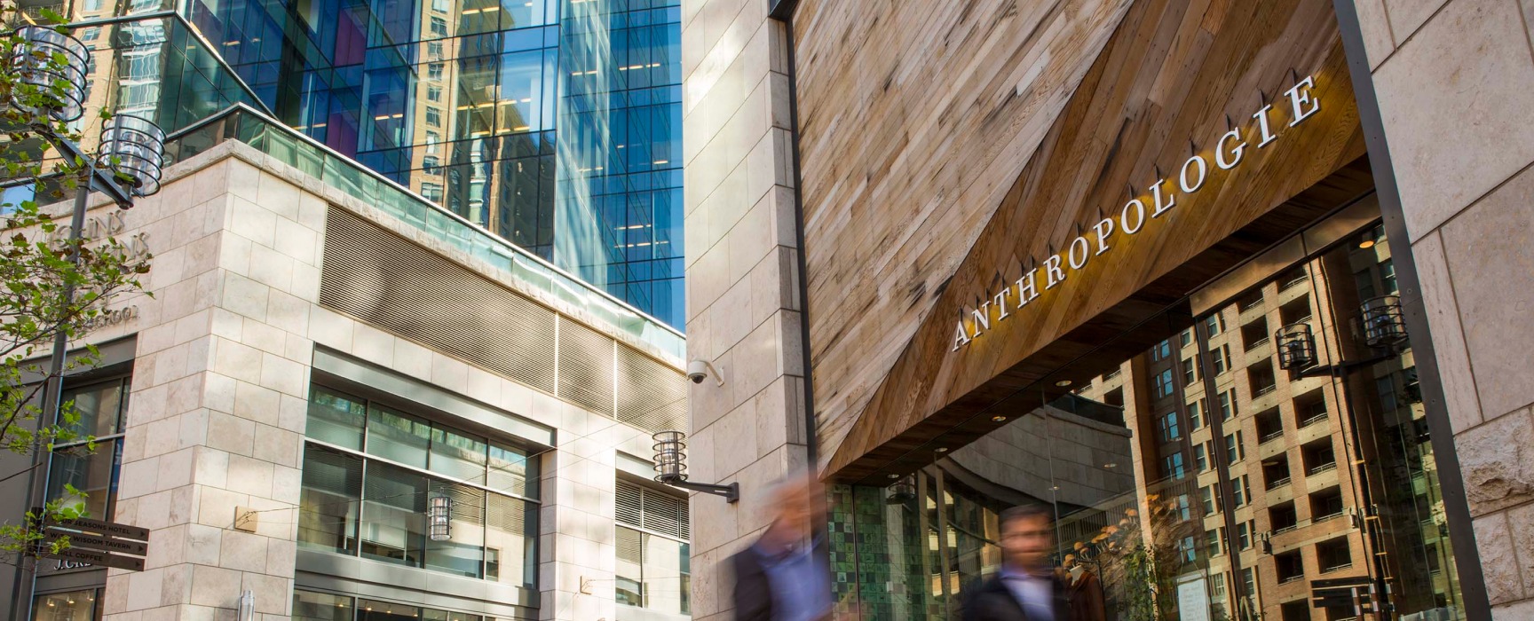 Two men whiz by the Anthropologie storefront in the center of Harbor East