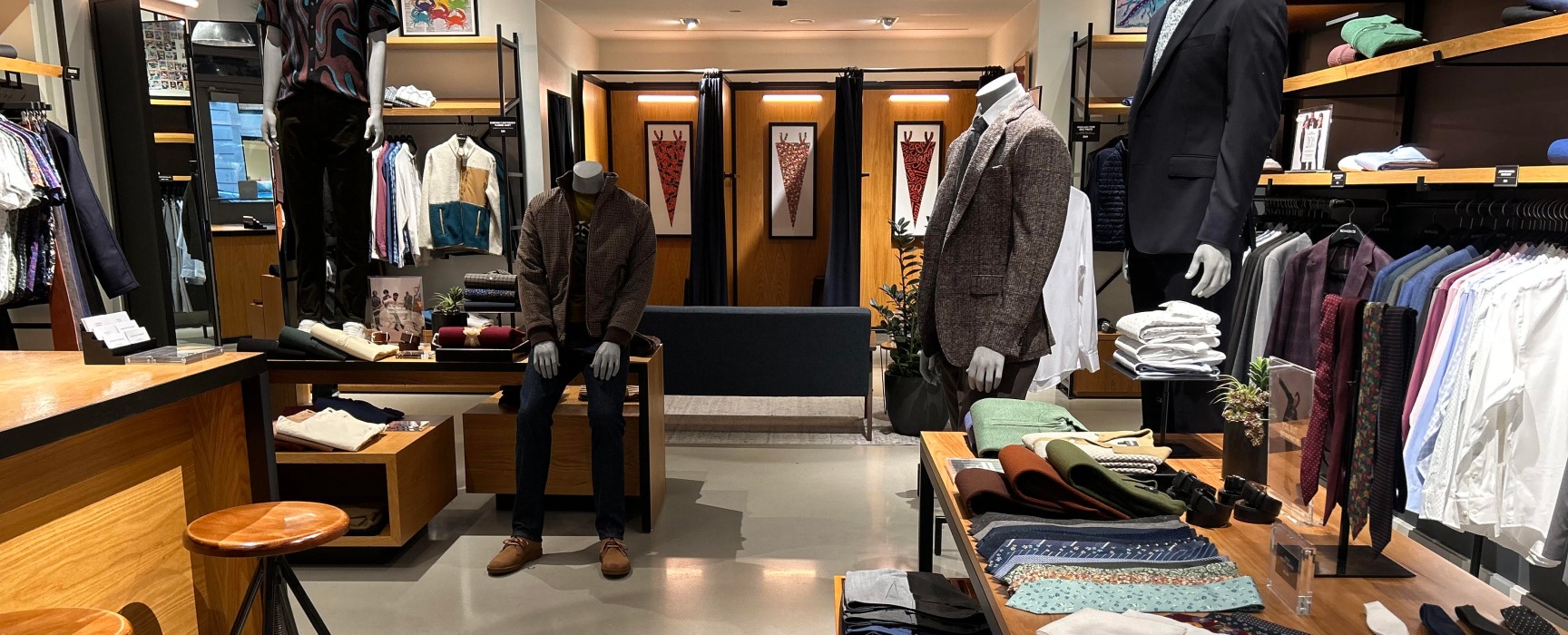 Interior of Bonobos retail store with mannequins outfitted in suits and displays with various ties and suit accessories