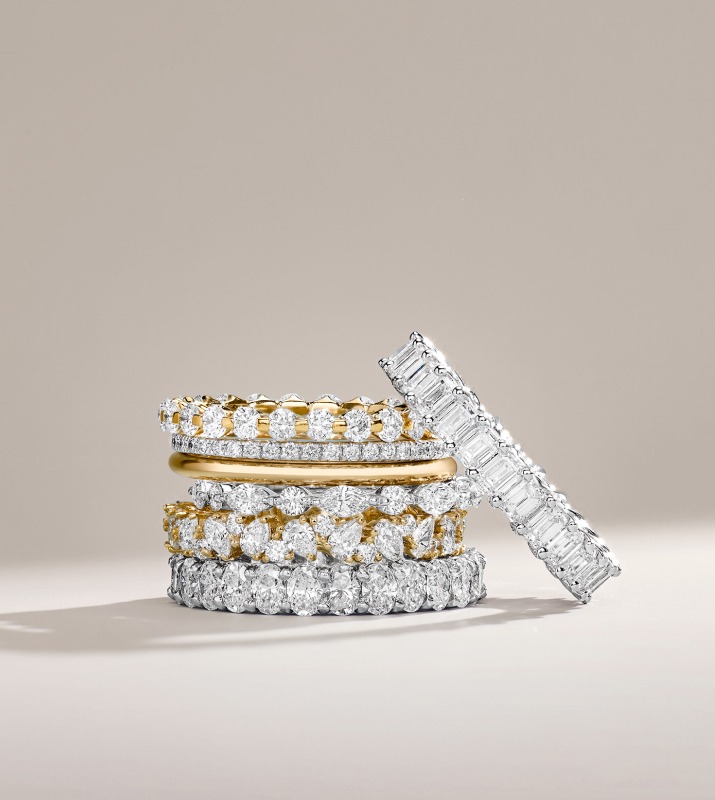 Stack of various white gold and silver diamond rings on clean, white studio backdrop