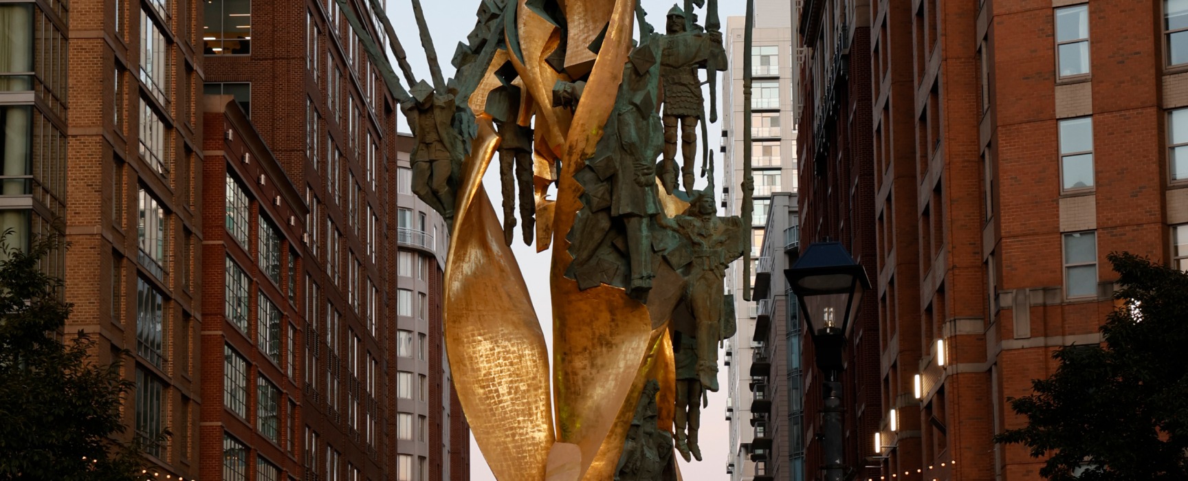 Gold statue in the center of Harbor East flanked by tall city buildings