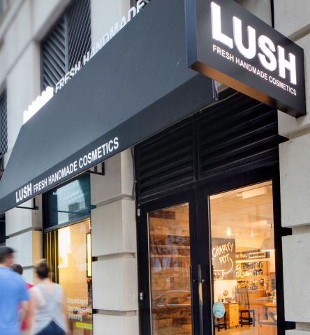 A group of people walk past the entrance of Lush cosmetics in Harbor East
