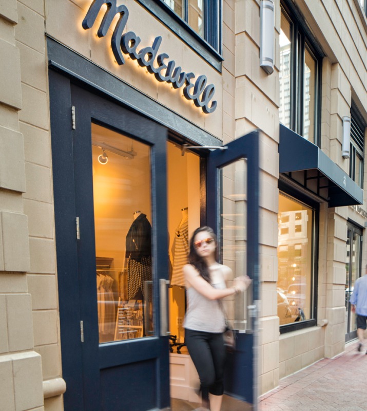 A women leaves through the entrance doors to Madewell, a modern clothing shop in the center of Harbor East