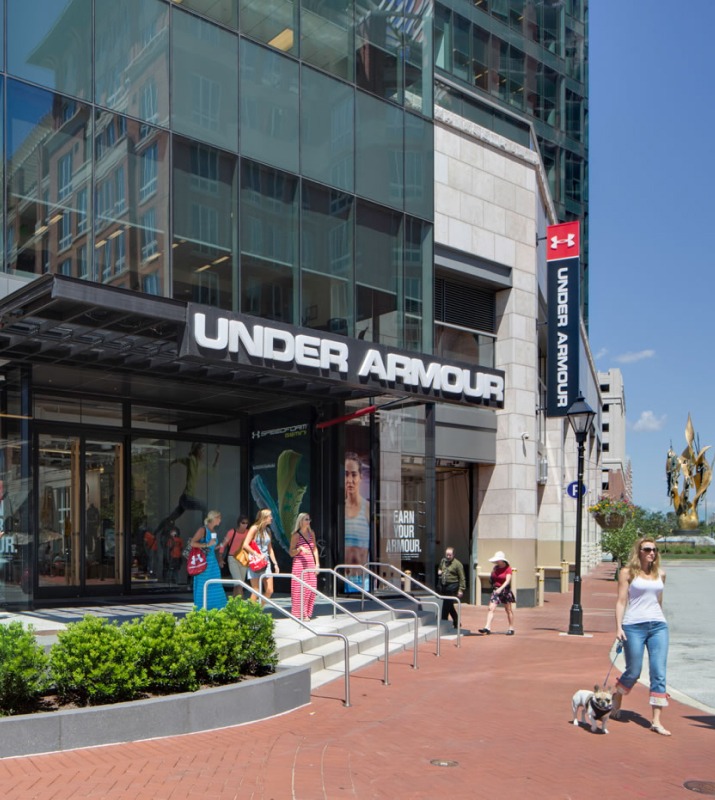 Several people walking past the Under Armour Brand House retail store on a sunny day on the promenade in Harbor East