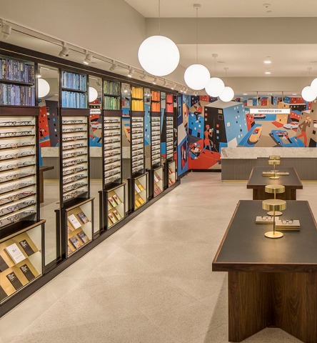 Colorful interior of Warby Parker, featuring modern glowy lighting, mural, and display rows of eyeglasses