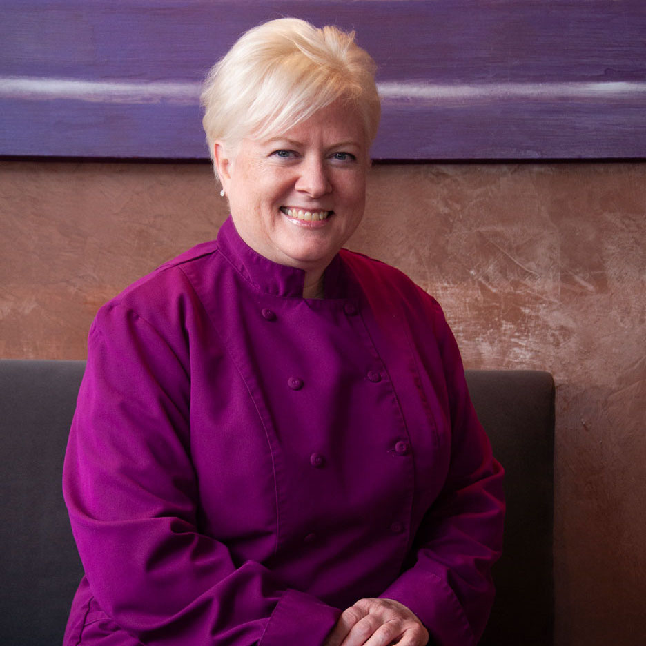 Headshot of Chef Cindy Wolf in purple chef work shirt