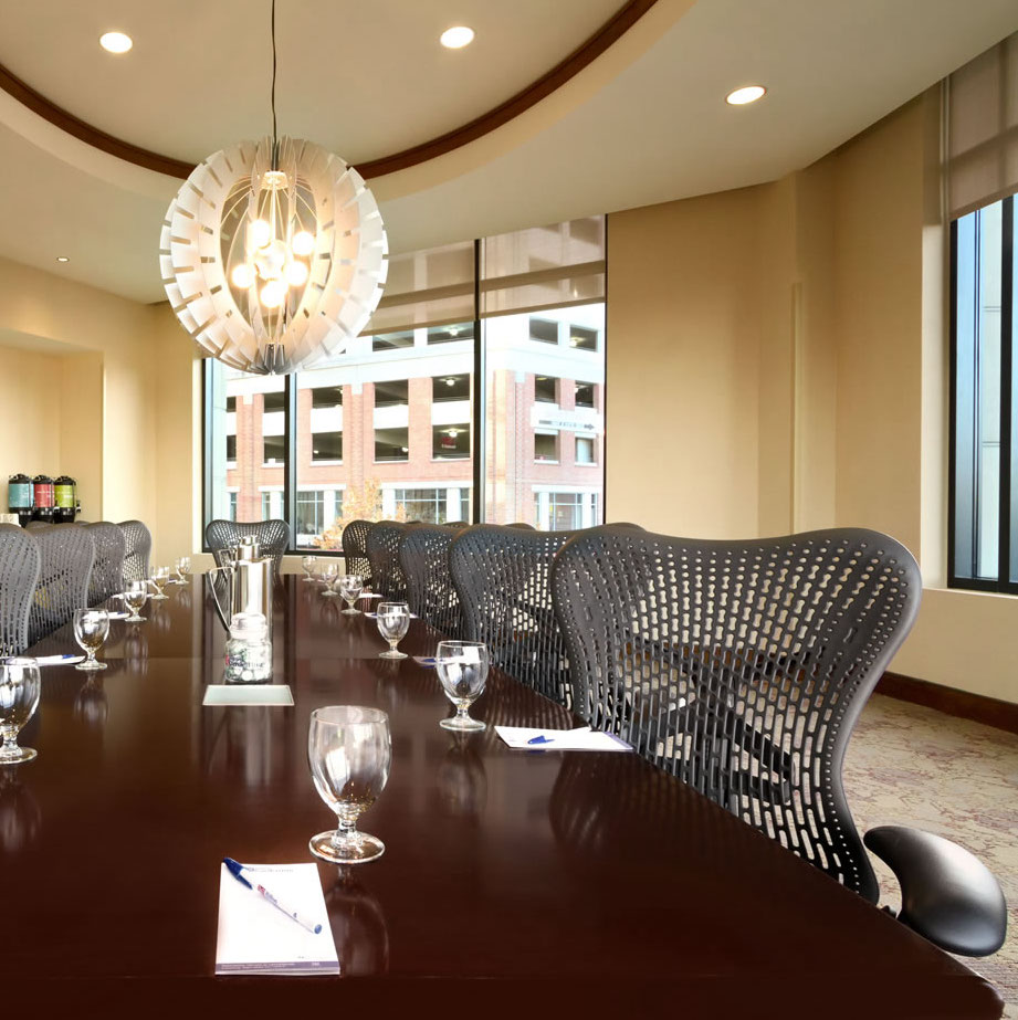 Interior of Homewood Suites hotel meeting room featuring long wooden table and neatly organized office chairs lining the table