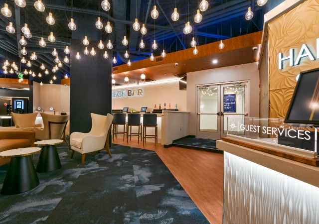 Interior of Harbor East Cinema lobby featuring theater bar, cozy seating, and hanging bulb light fixtures