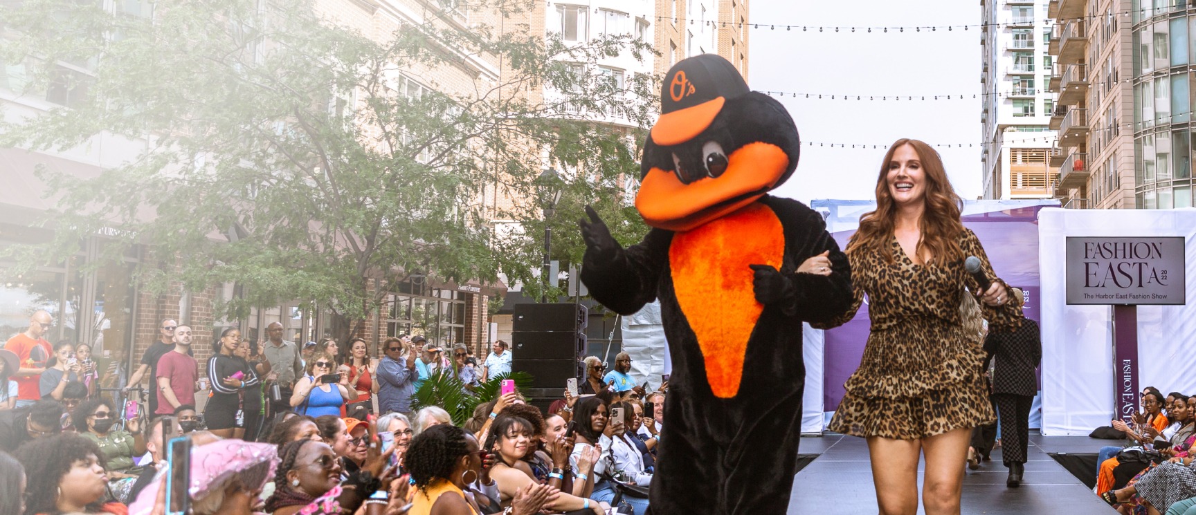 The Oriole Bird Mascot and a host strut down the outdoor runway at FashionEASTa 2022