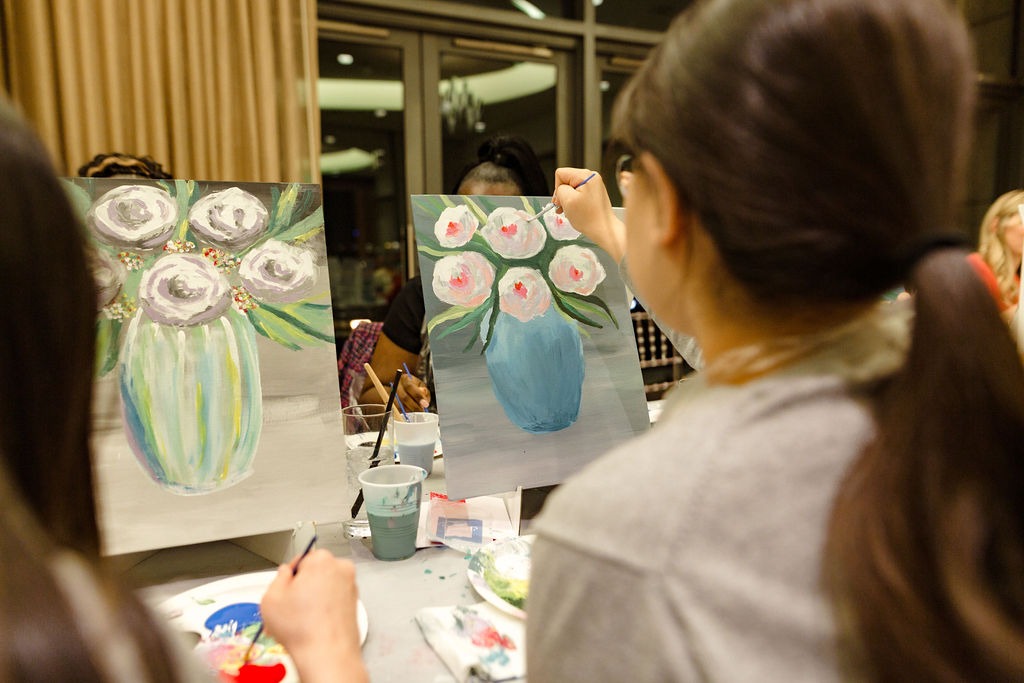 guest painting flowers at paint and sip night at four seasons