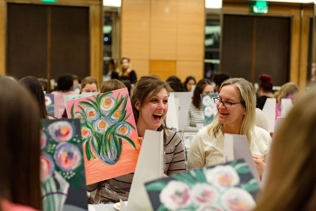 guest showing her painting of flowers to her friends